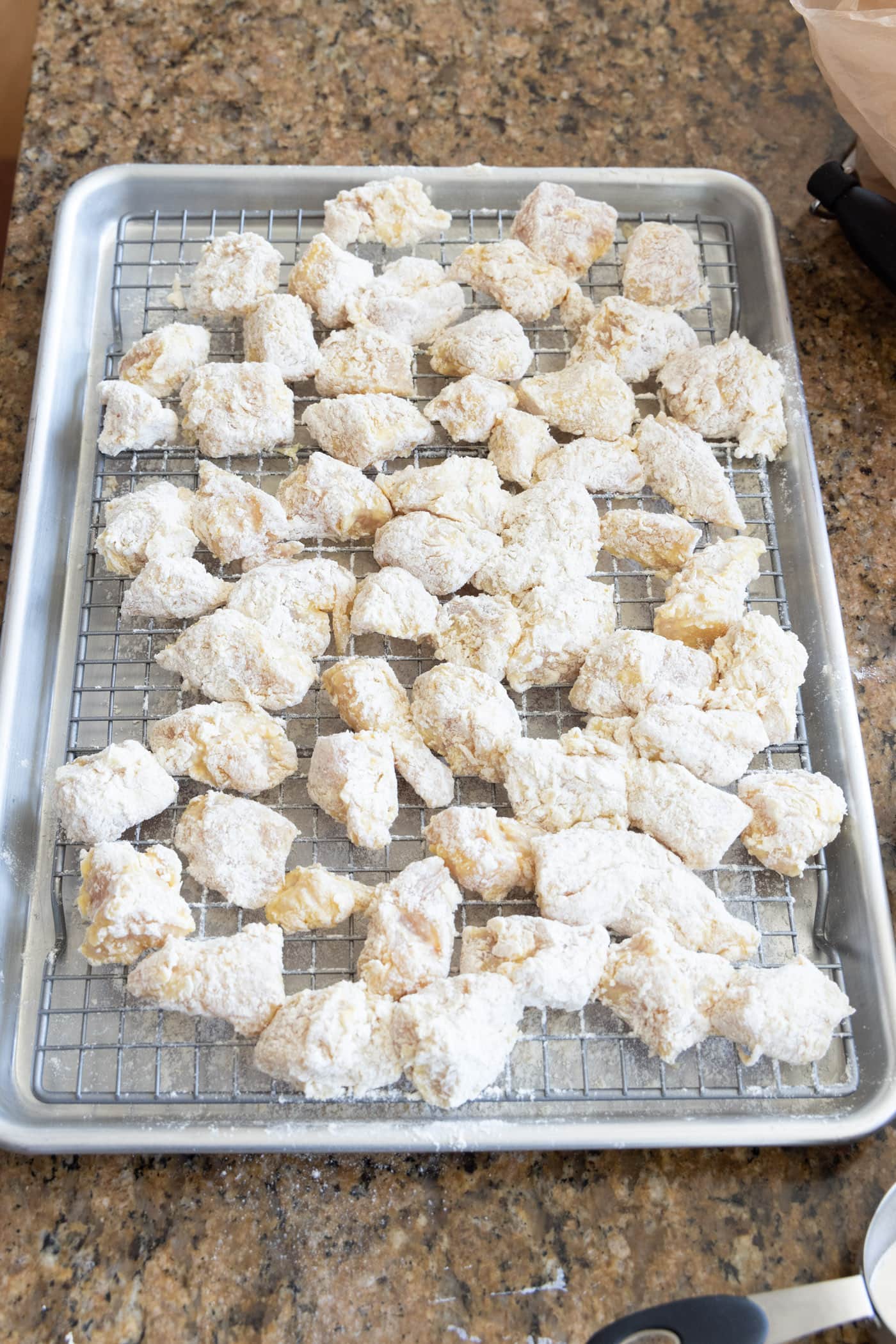 flour and egg dredged chicken pieces on a wire rack