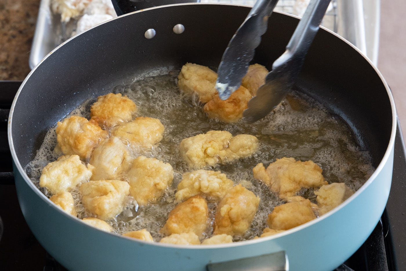 flipping chicken in a skillet of oil