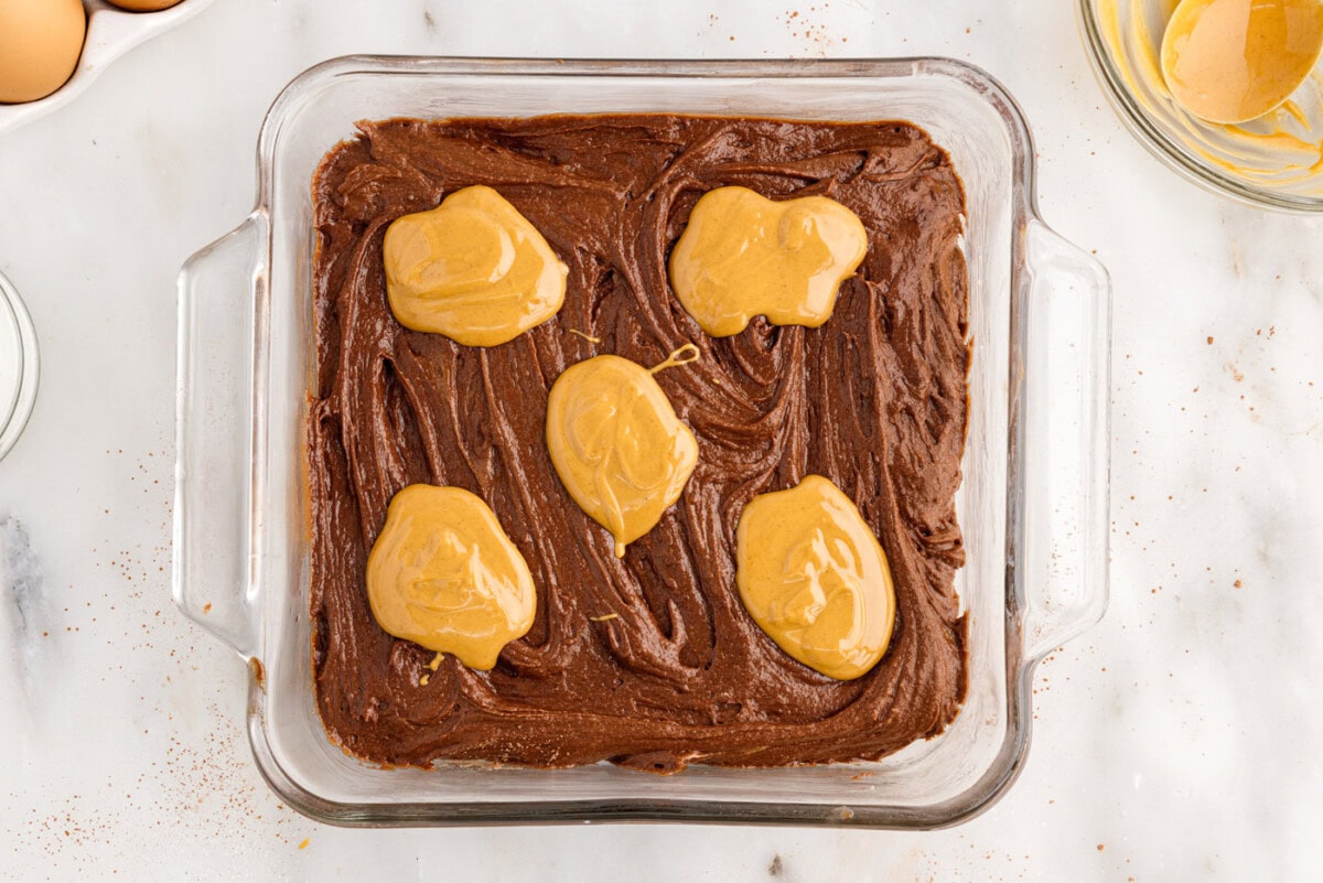 dollops of melted peanut butter on top of brownie batter