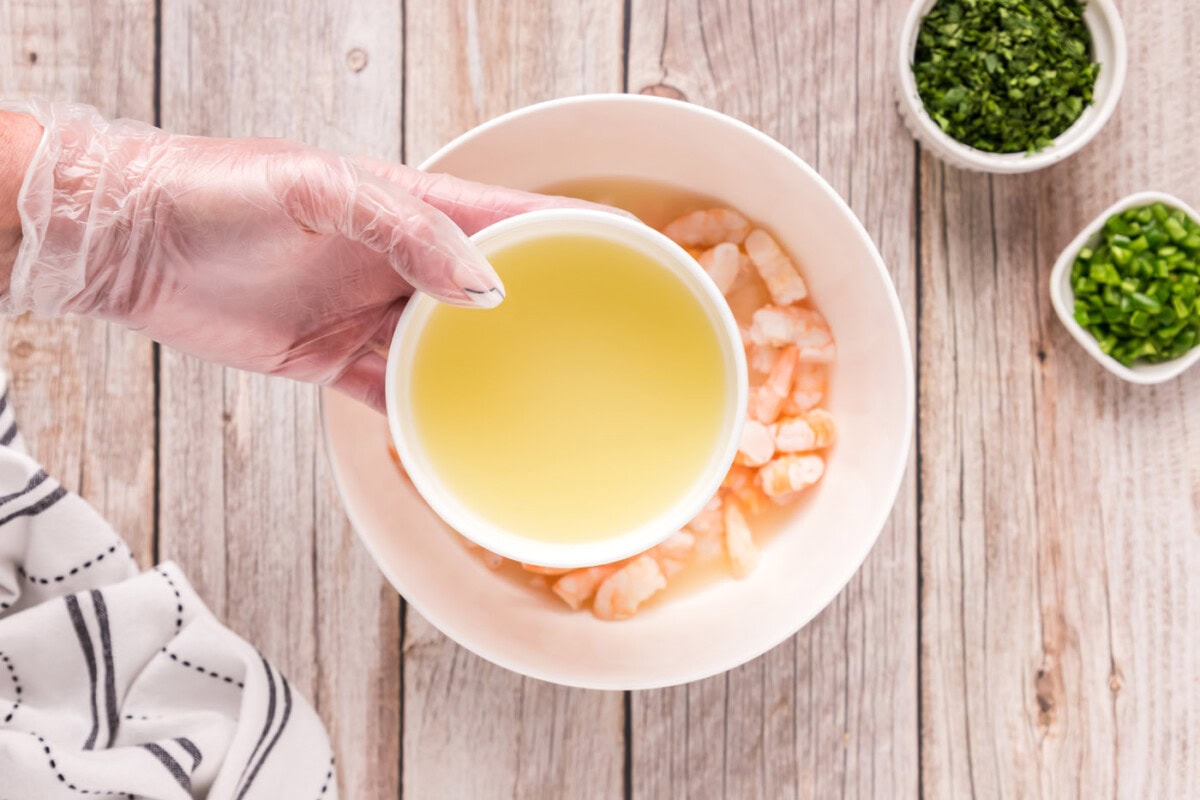 adding lemon and lime juice to shrimp