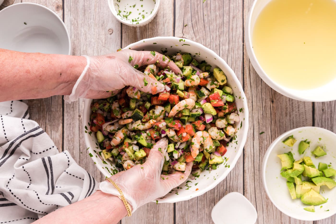 hands mixing shrimp ceviche in a bowl