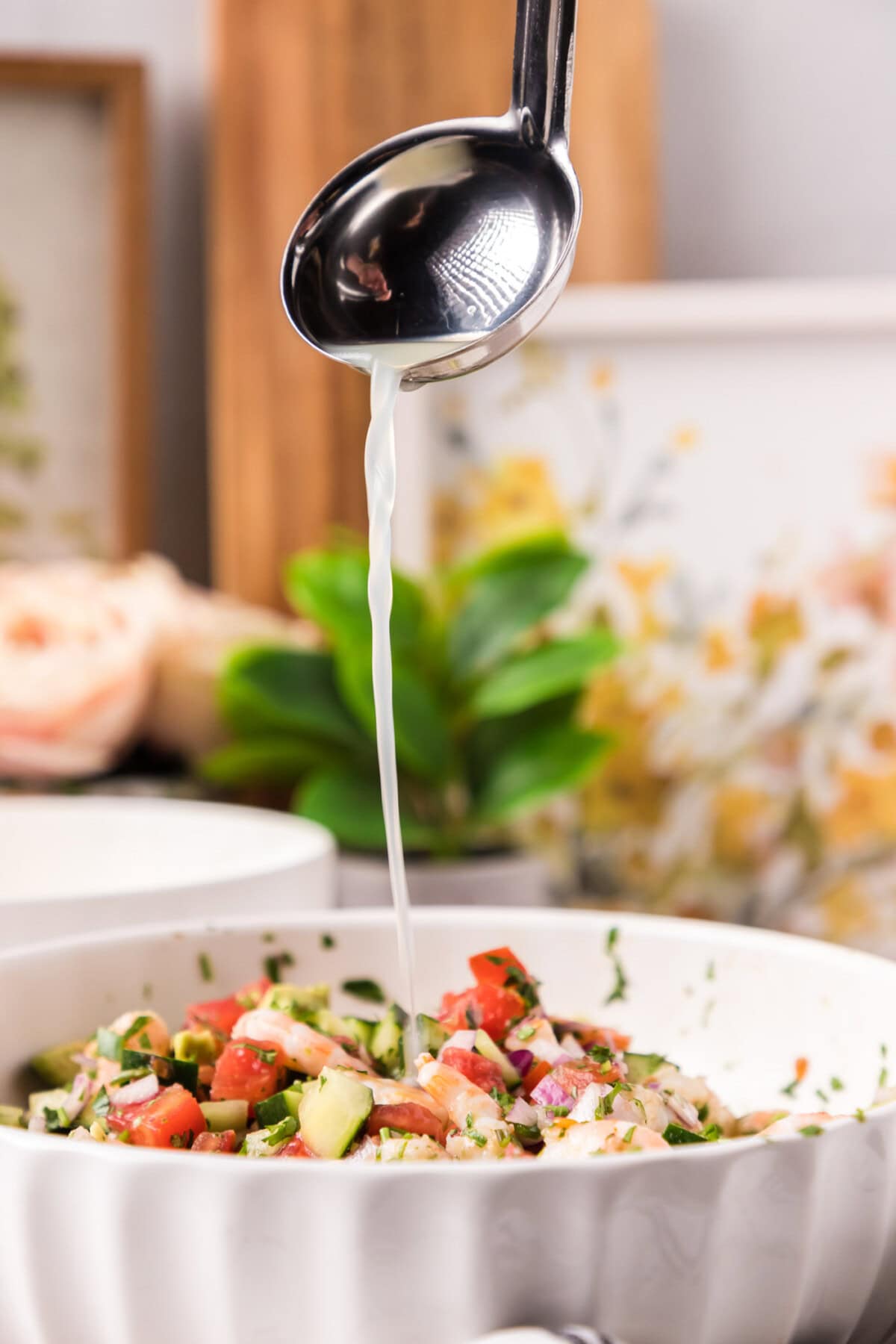 Ladle of fruit juices being poured into a bowl of Shrimp Ceviche