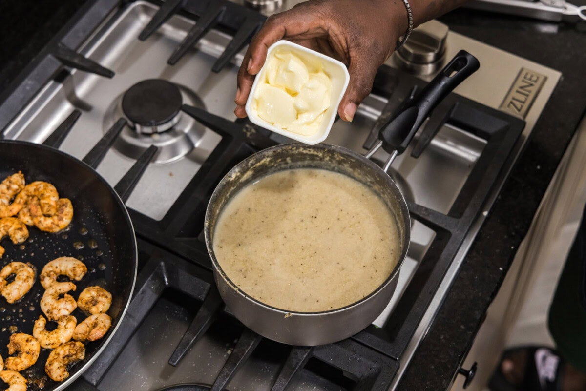 adding butter to grits in a saucepan