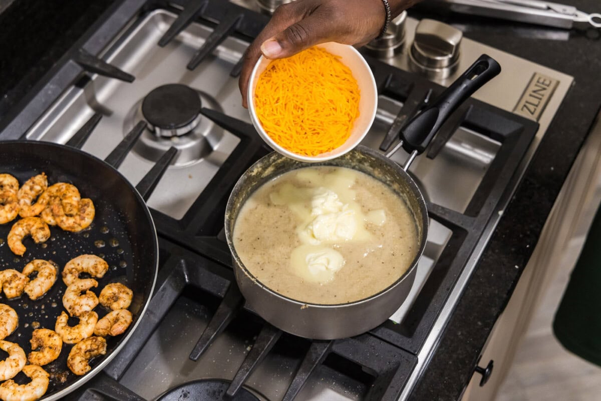 adding cheddar cheese to grits in a saucepan