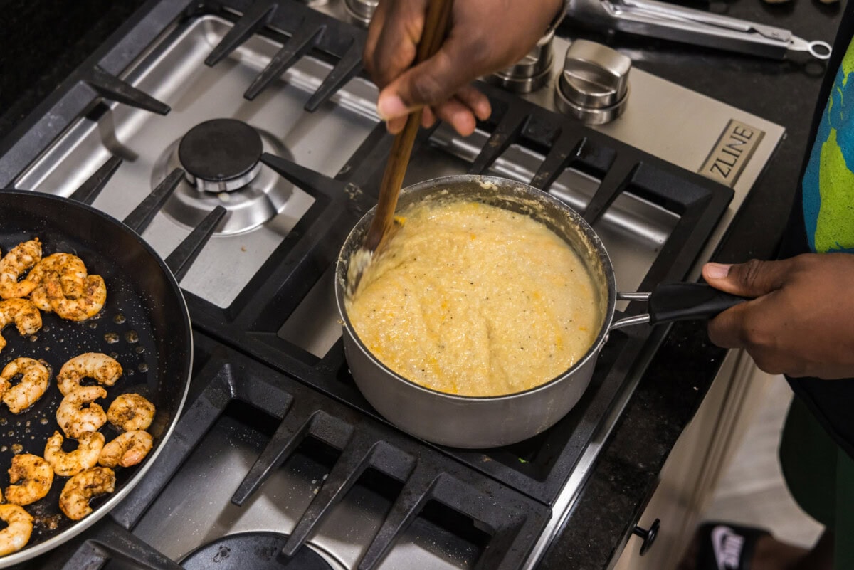 stirring cheesy grits in a pot