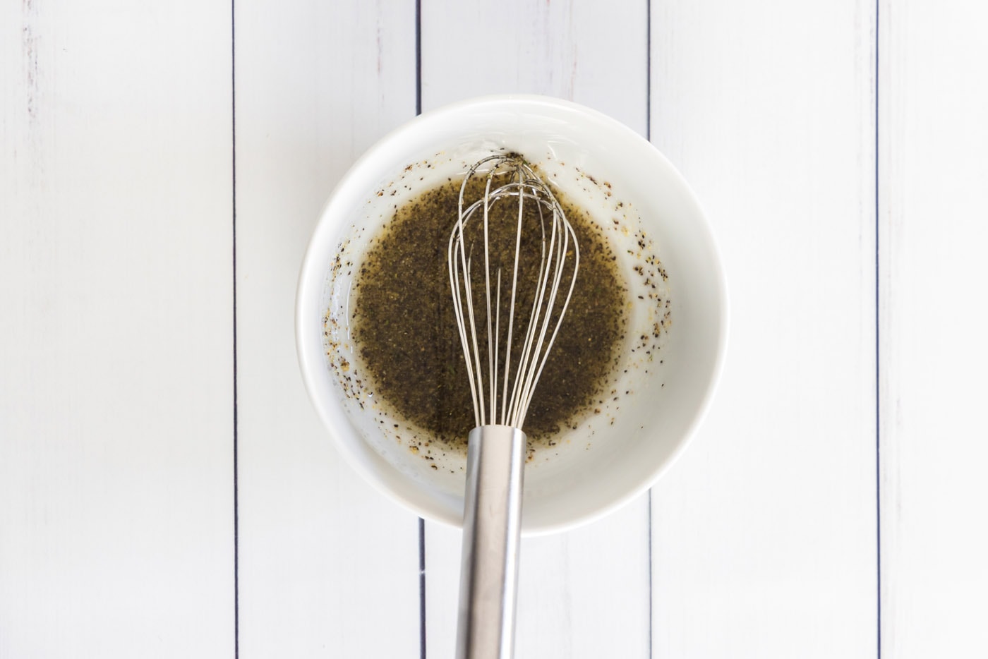 whisking olive oil, salt, and pepper in a bowl