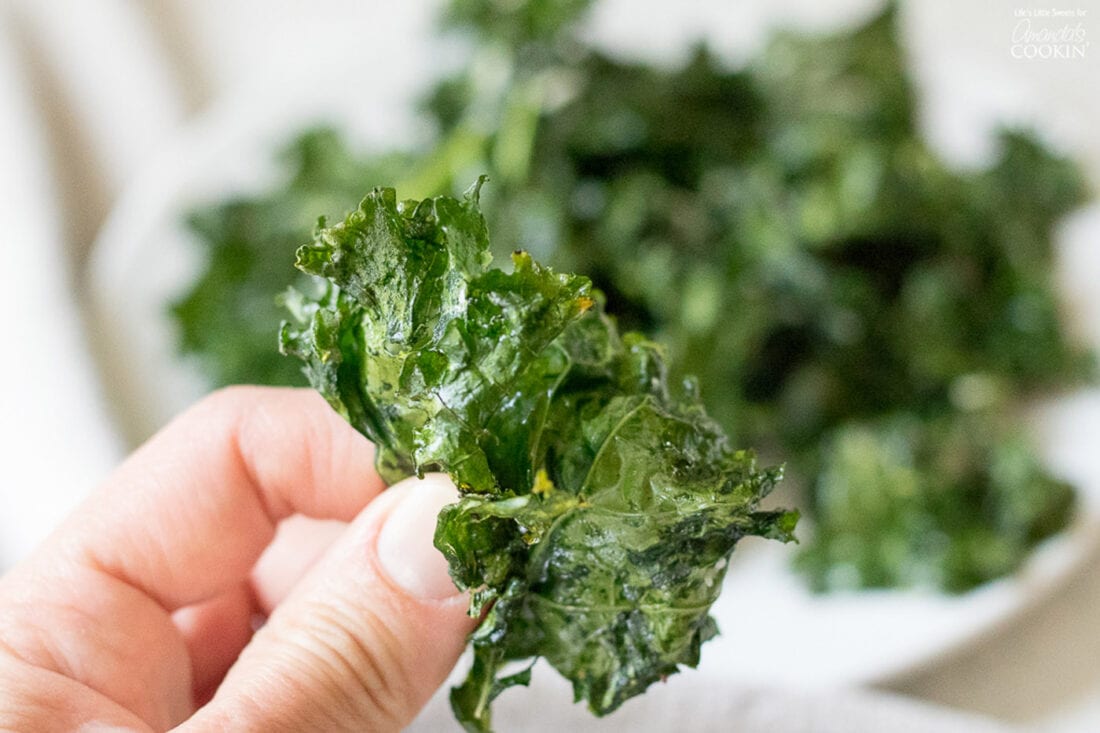 Close up of a kale chip with Kale Chips in the background 