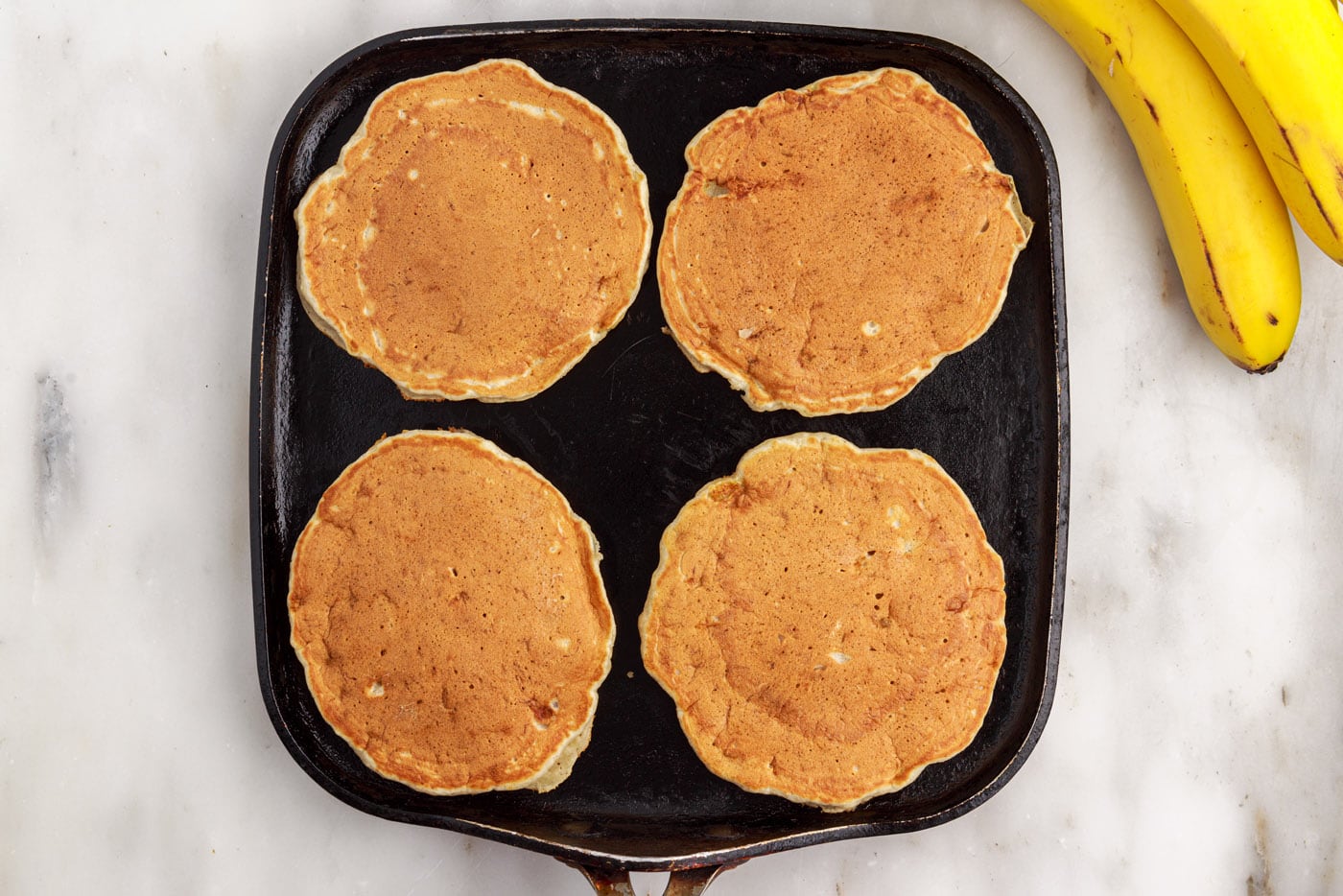golden brown banana pancakes on a griddle