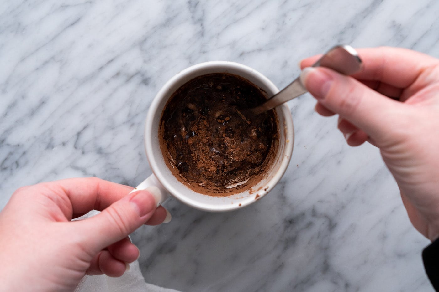 stirring brownie in a mug ingredients in a cup