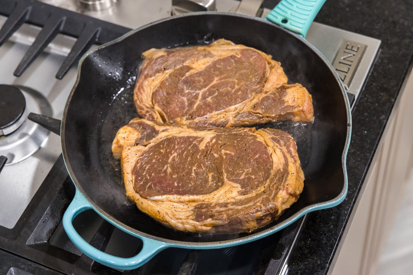 marinated ribeye steaks in a cast iron skillet