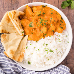 Close up of a bowl of Chicken Tikka Masala with rice and naan bread