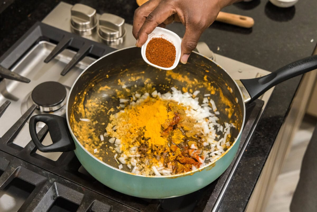 hand adding seasonings to skillet