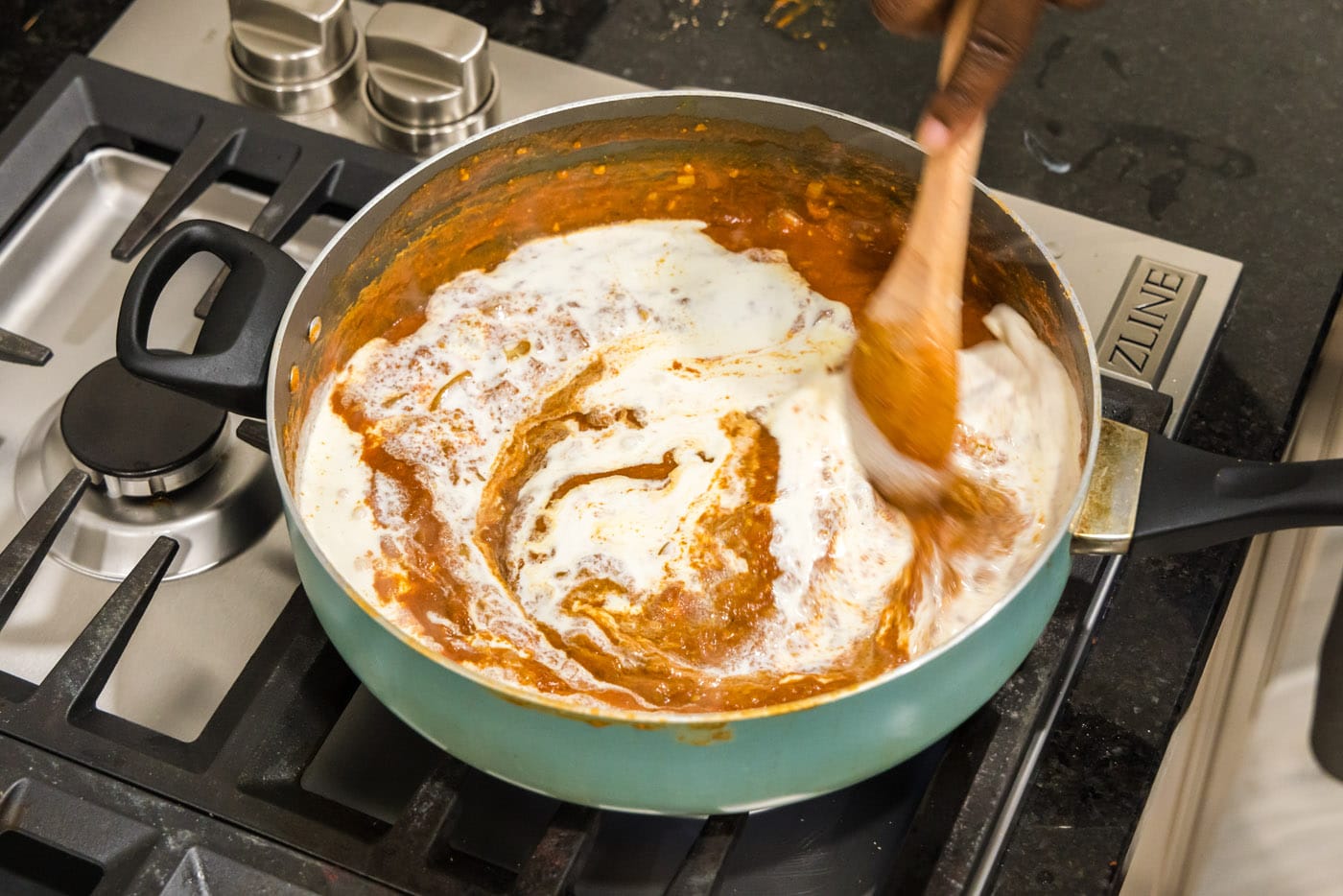 stirring chicken tikka masala sauce in a skillet