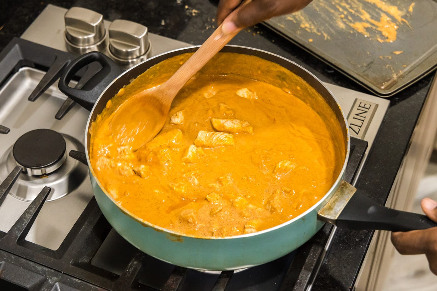 stirring chicken into tikka masala sauce