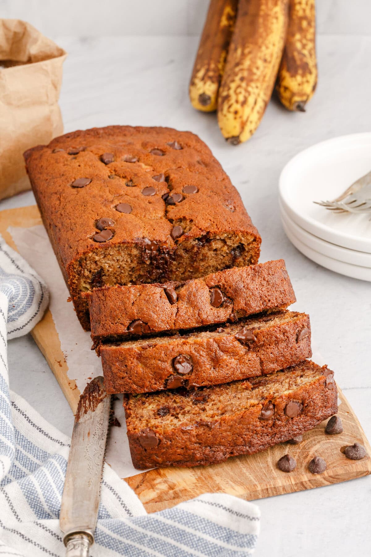 Loaf of Chocolate Chip Banana Bread sliced on a wooden cutting board