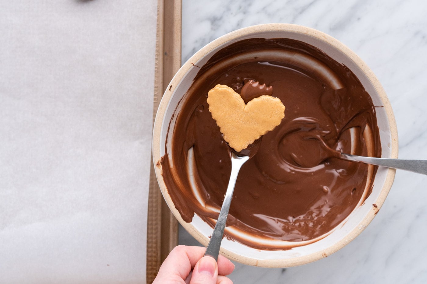 dipping peanut butter heart into melted chocolate with a fork