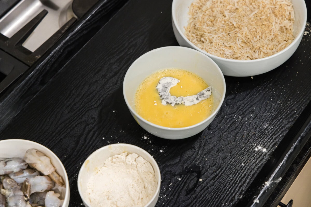 dipping floured shrimp into egg