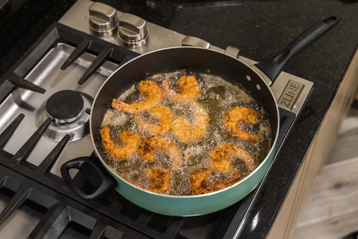 coconut breaded shrimp in a skillet of oil