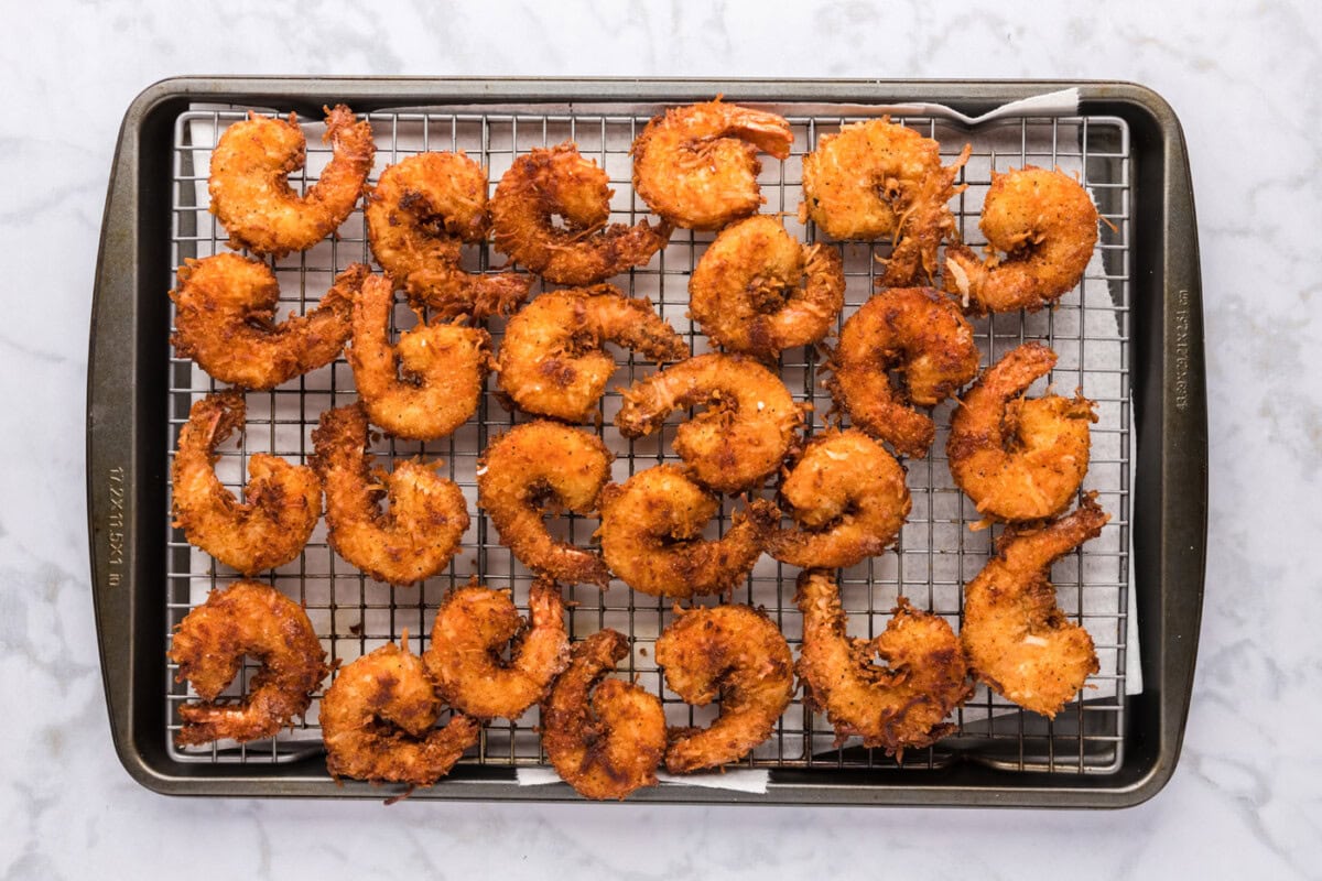 golden coconut shrimp cooling on a wire rack