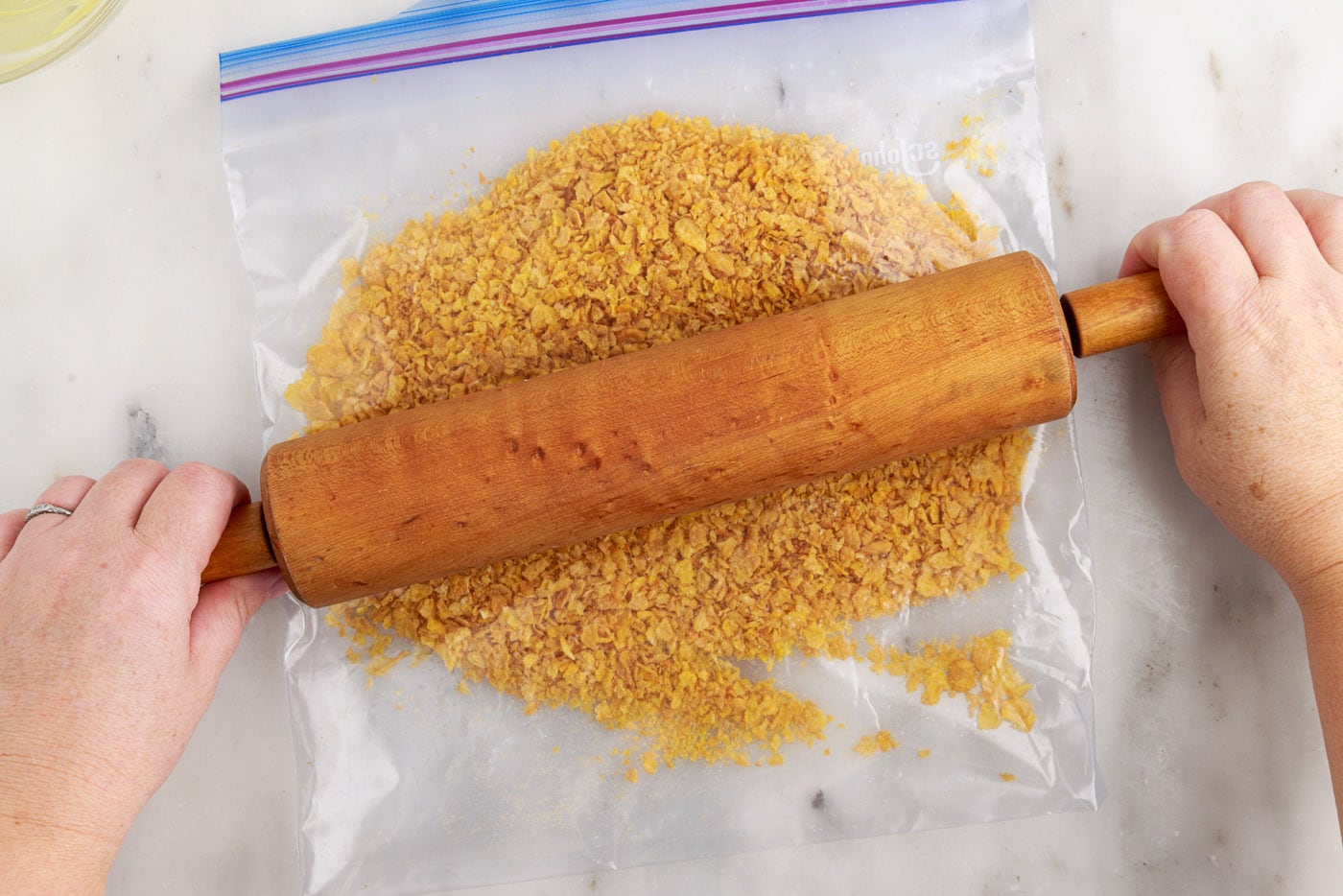 crushed cornflakes in a bag with rolling pin