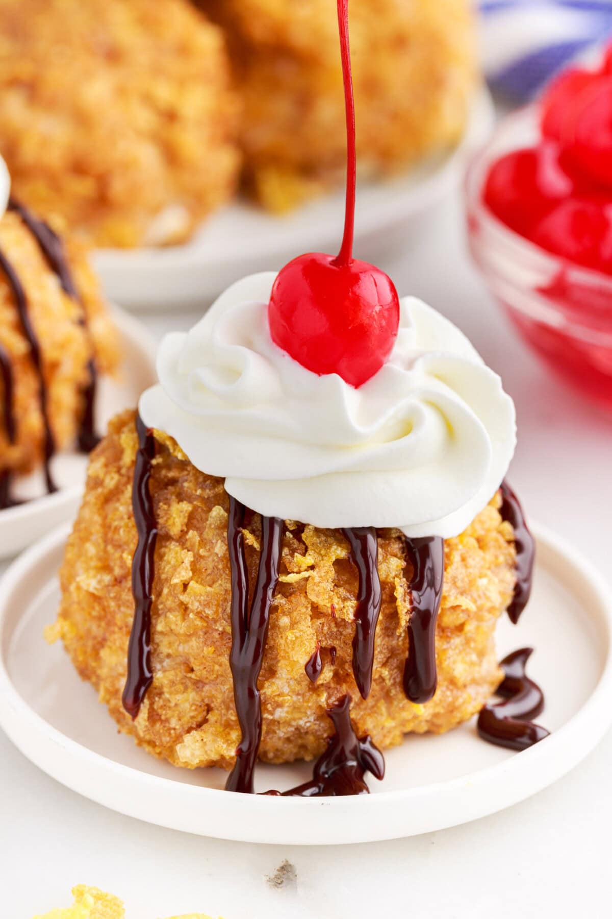 Fried Ice Cream on a plate with whipped cream and a cherry on top