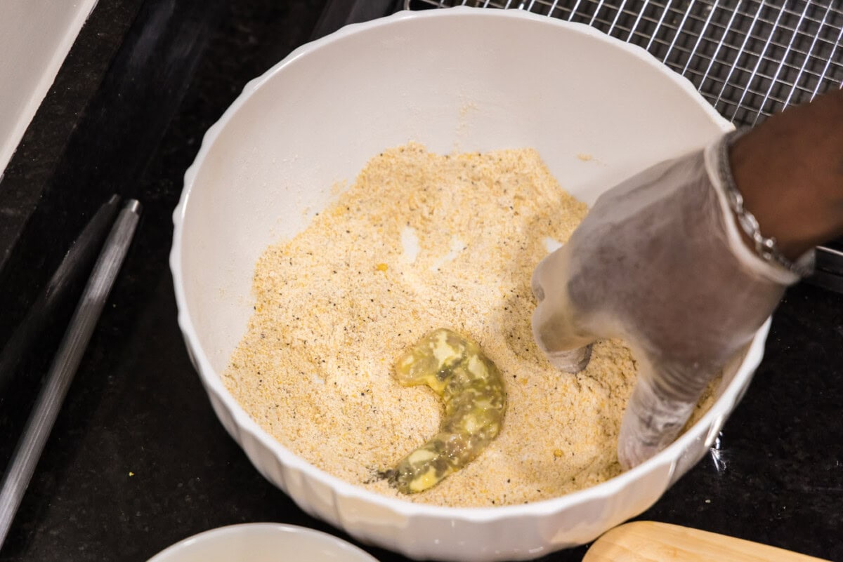 dredged shrimp in a bowl with cornmeal mixture