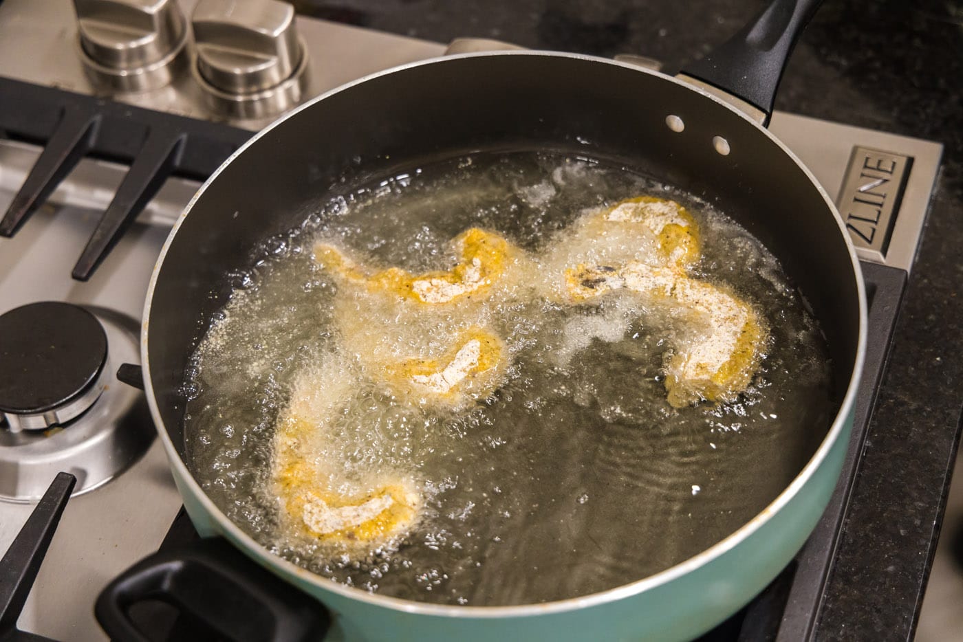 frying breaded shrimp in a skillet of oil