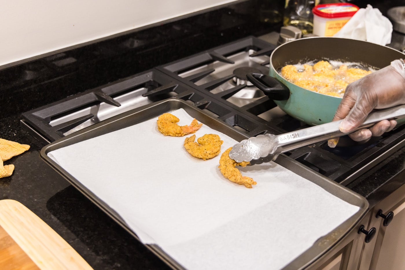 removing fried shrimp from oil and placing on paper towels