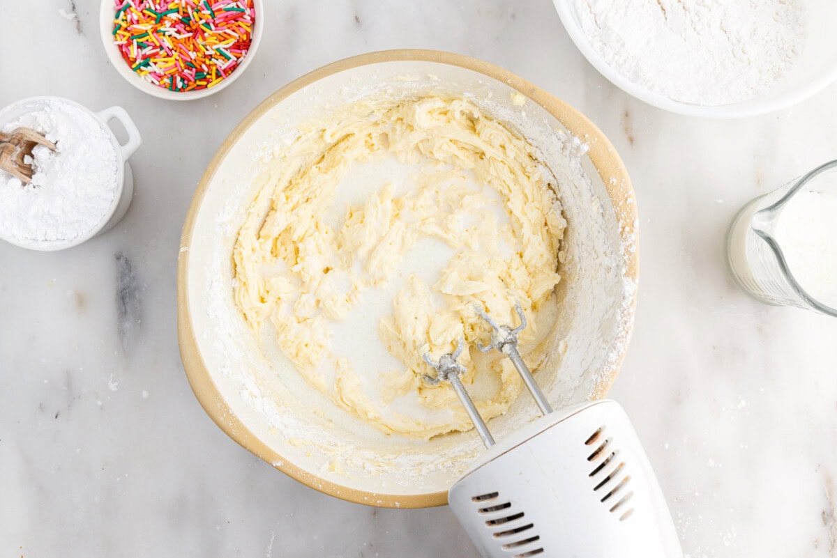 adding milk to cake batter in a bowl