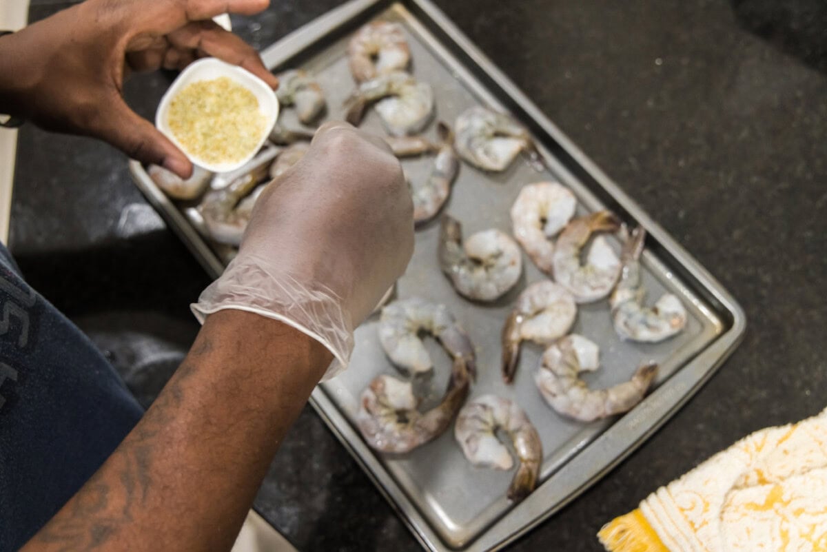 seasoning shrimp on a baking sheet