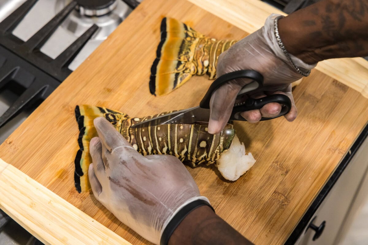 using kitchen shears to cut down the center of lobster tails