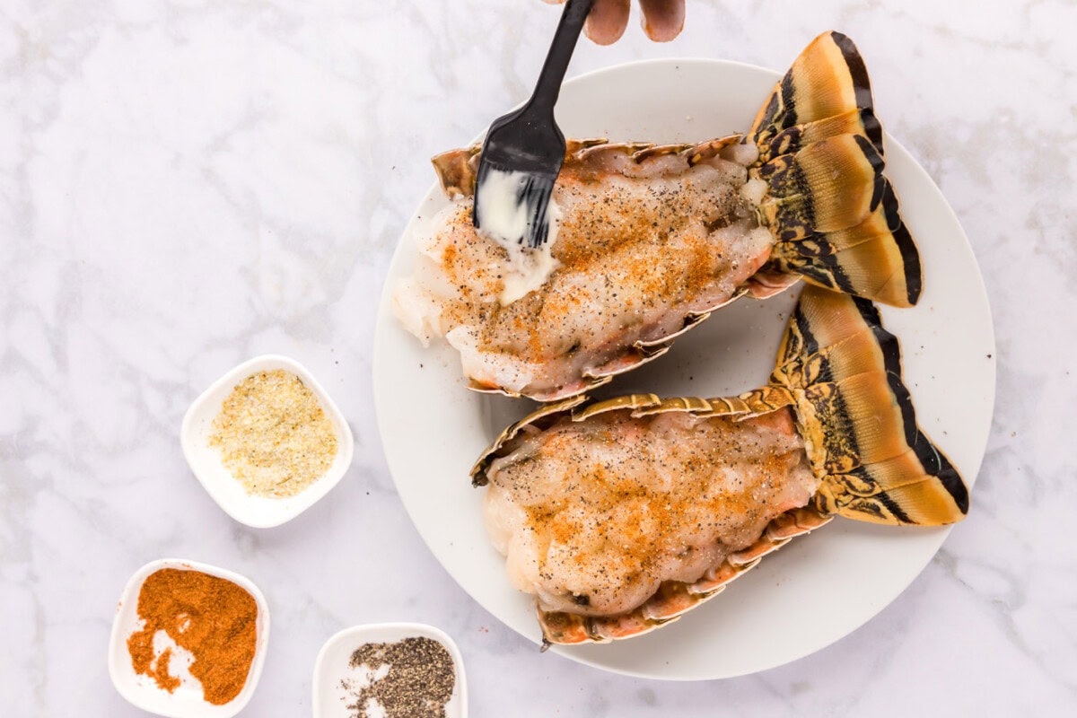 brushing seasoned lobster tail meat with butter