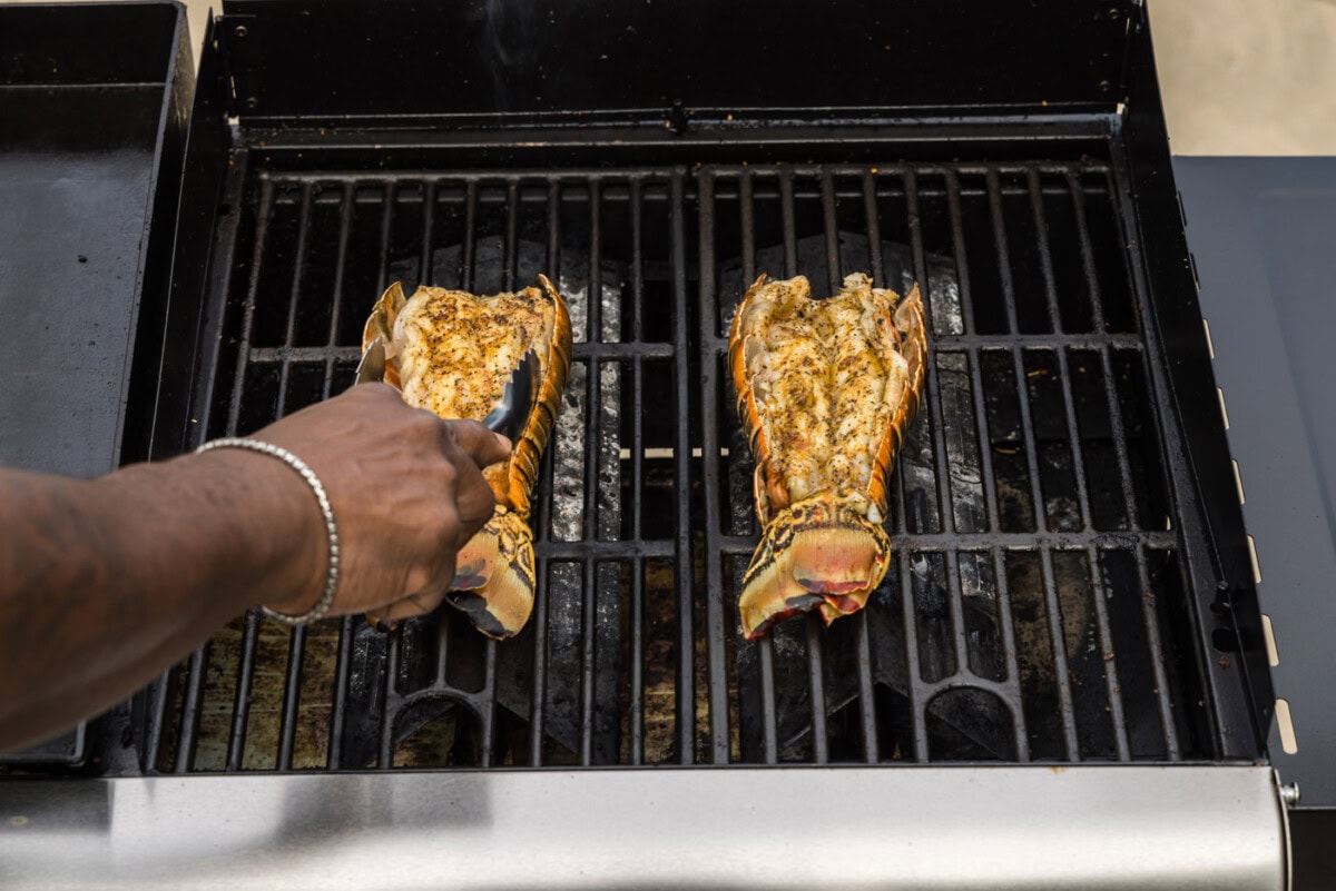 tongs flipping lobster tails over on the grill