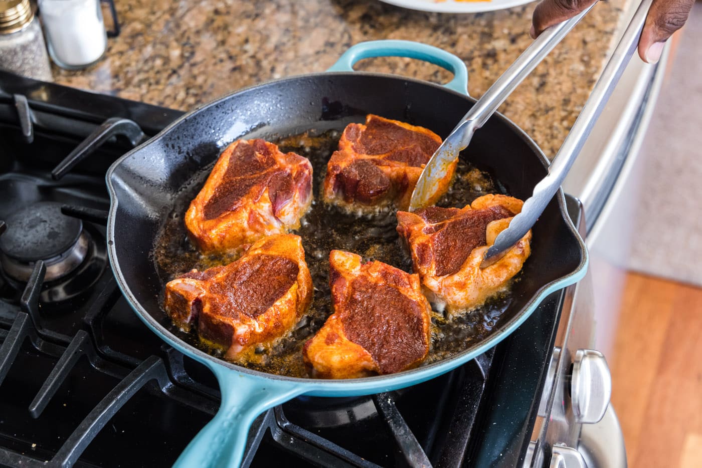 turning lamb loin chops over in a skillet with tongs