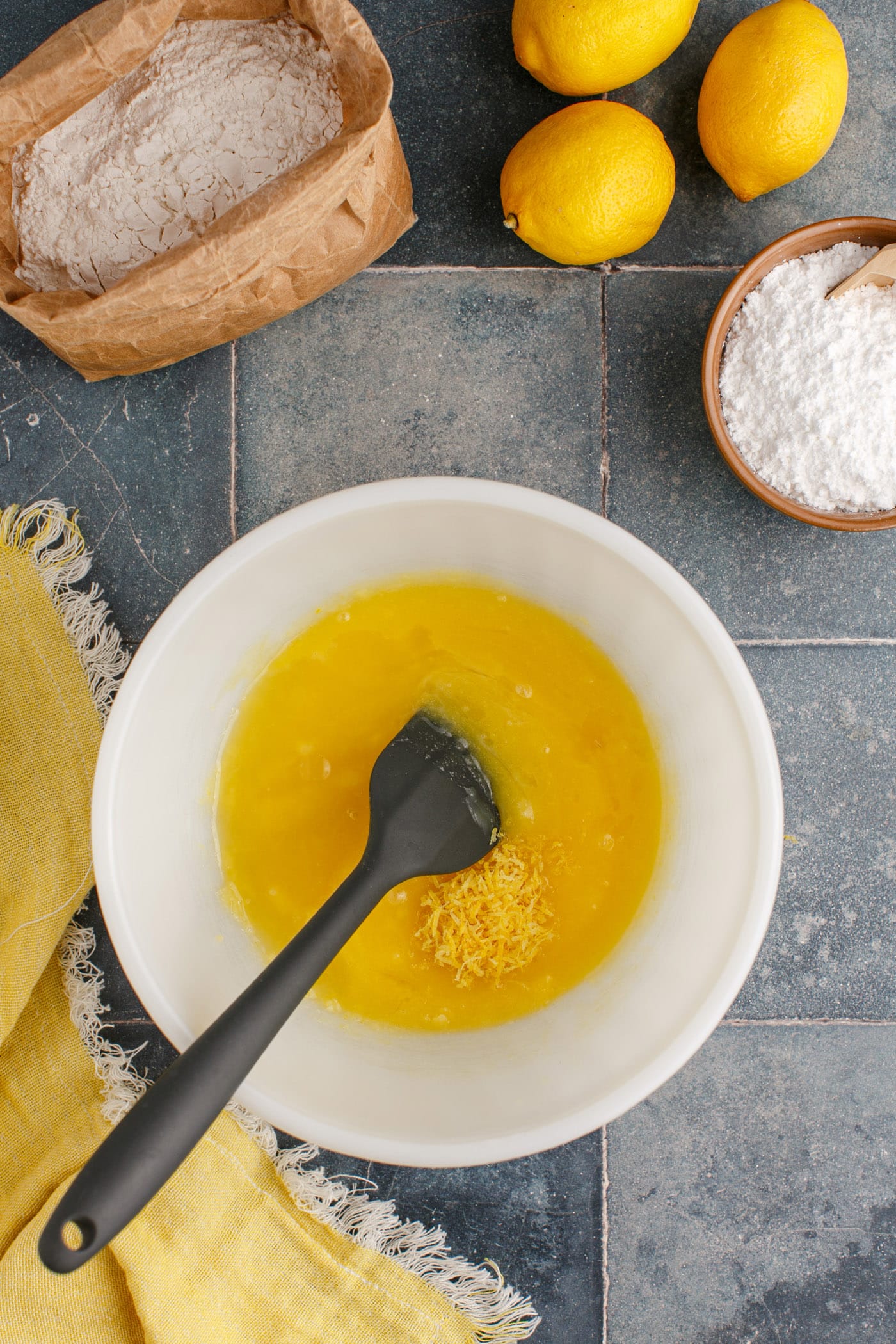 lemon juice and zest added to butter mixture in bowl with spatula