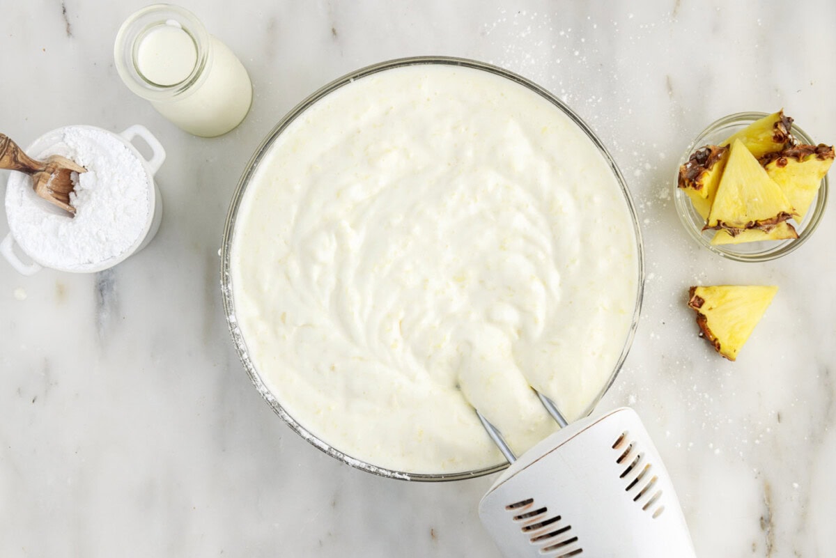 hand mixer combining crushed pineapple and angel food cake mix