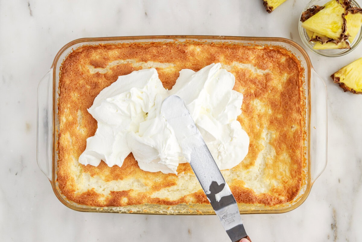 icing spatula spreading whipped cream onto angel food cake