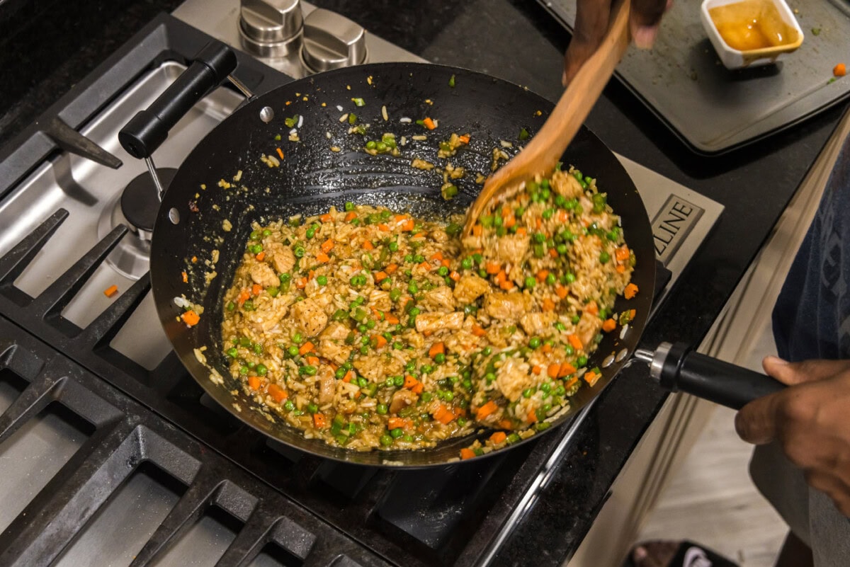 mixing pork fried rice in a wok with a wooden spoon