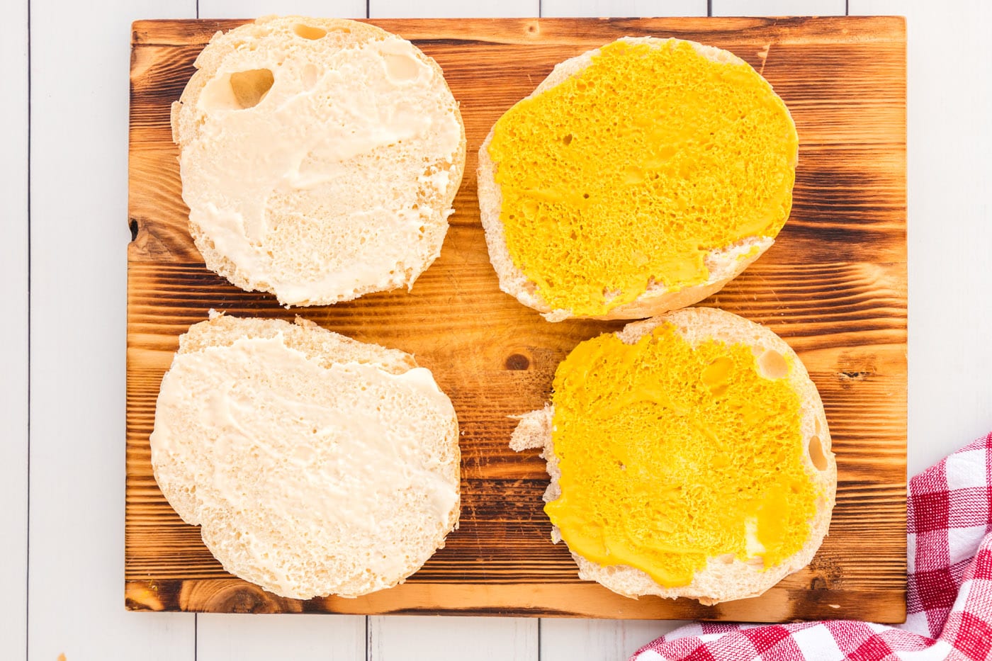 adding horseradish mayo and mustard to a sandwich bun