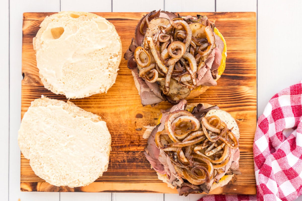glazed onions and sliced potatoes on top of a roast beef sandwich