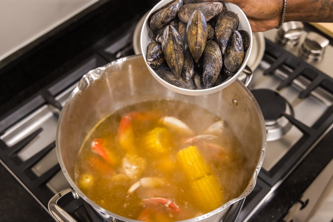 adding mussels to pot with seafood boil