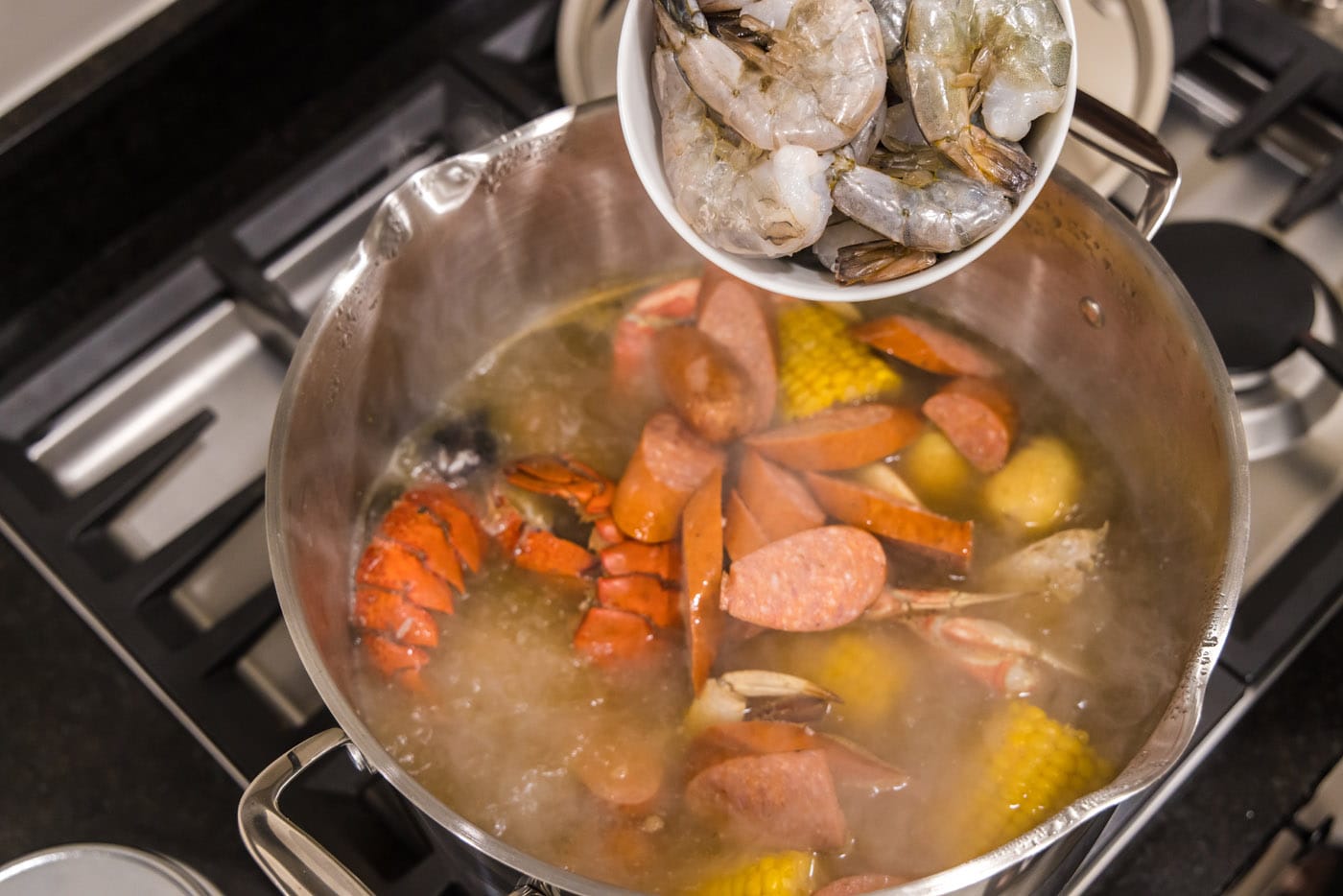 adding shrimp to pot with seafood boil