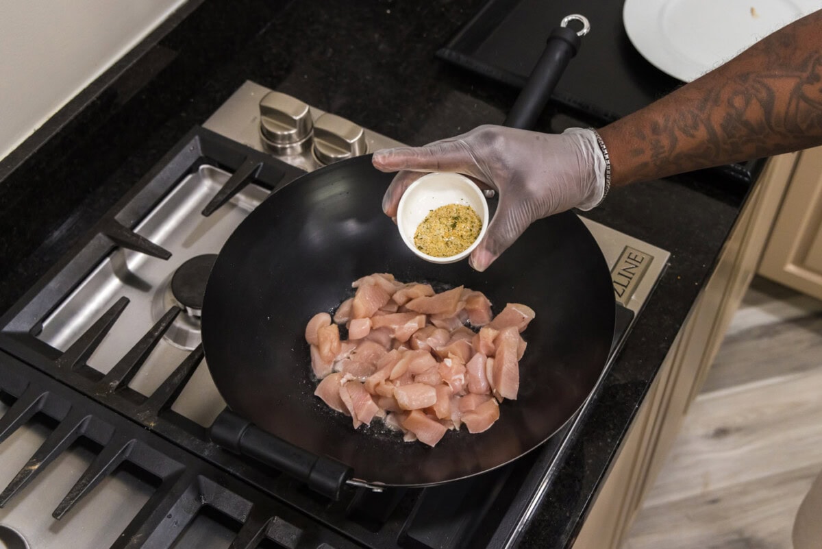 seasoning chicken in wok with garlic salt