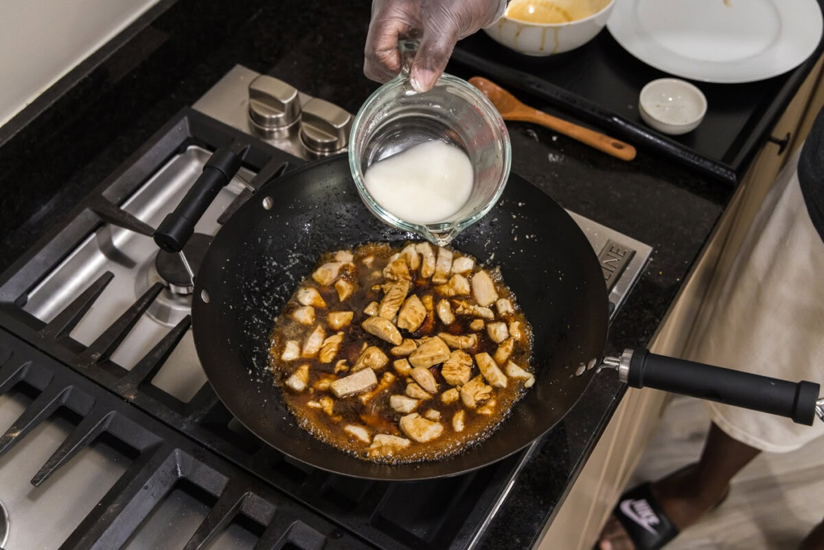 adding cornstarch slurry to wok with teriyaki chicken
