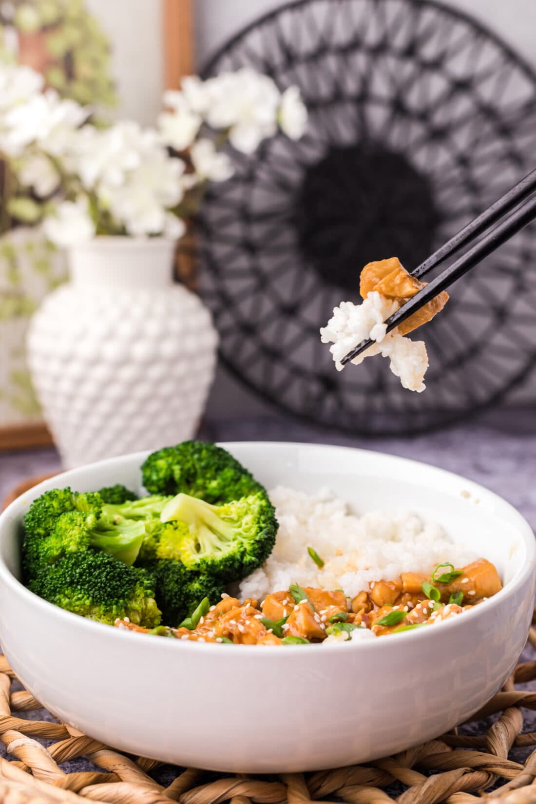 Chopsticks holding a piece of Teriyaki Chicken  and rice