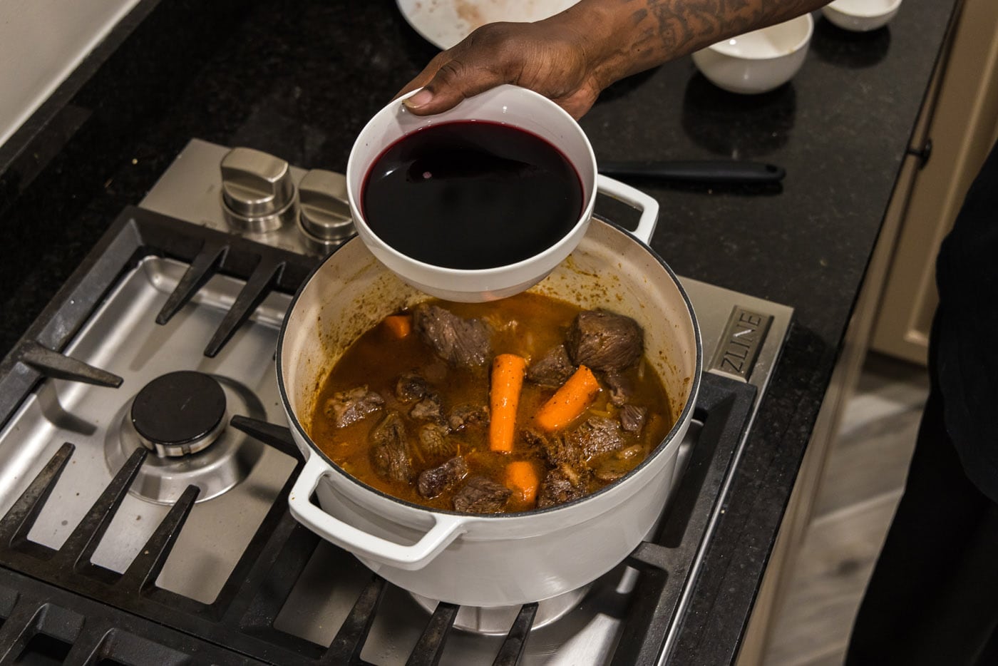 red wine added to braised beef in a dutch oven