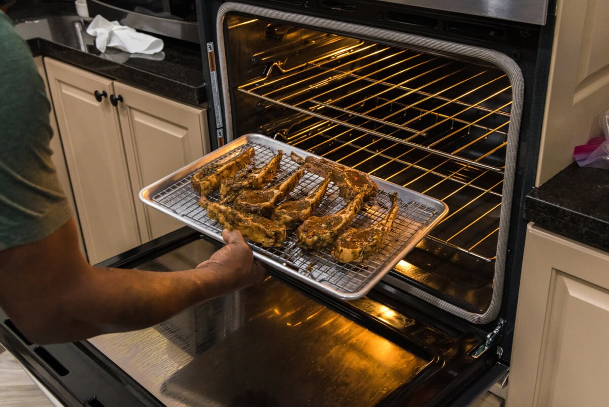 placing baking sheet with lamb chops under the broiler
