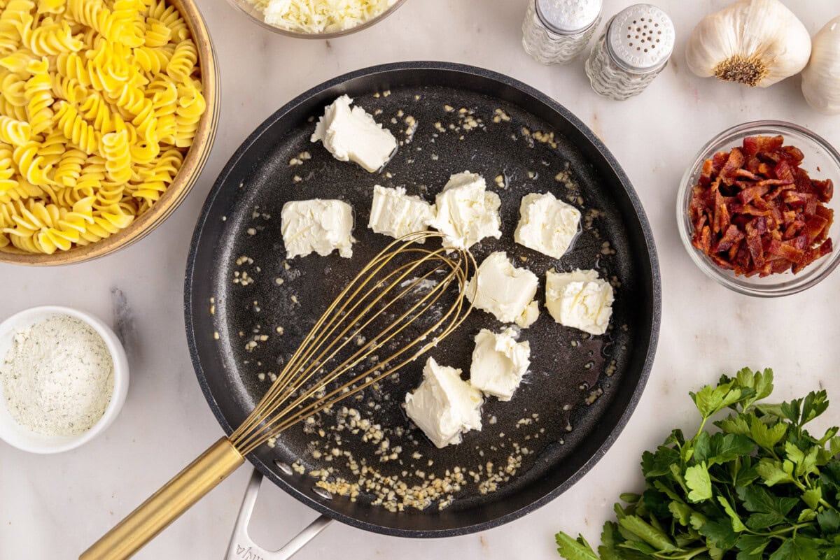 whisking cream cheese into skillet with garlic