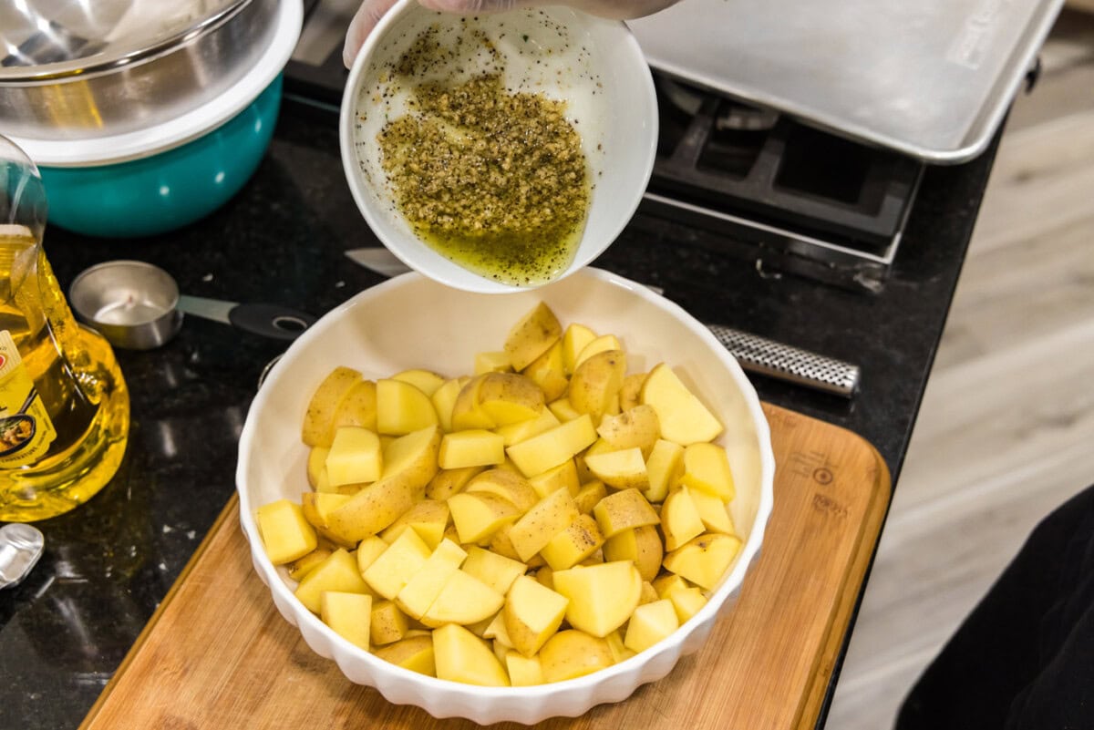 pouring garlic seasoned olive oil on top of potatoes
