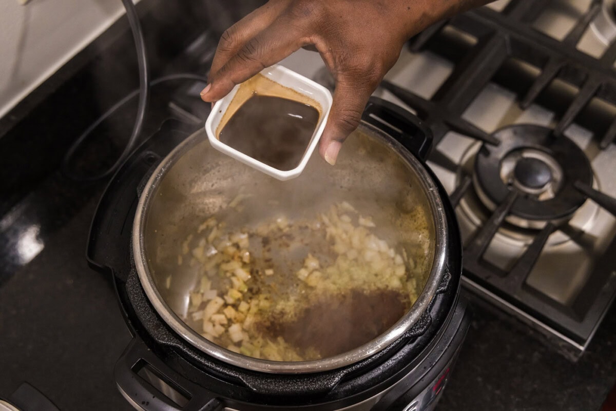 adding Worcestershire sauce to onions and seasonings in the instant pot
